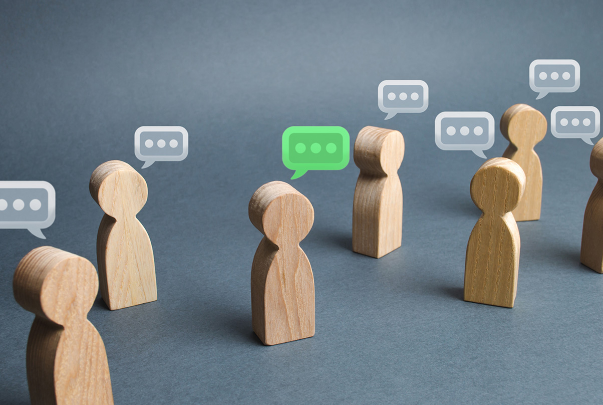 Wooden figures with speech bubbles representing communication and discussion